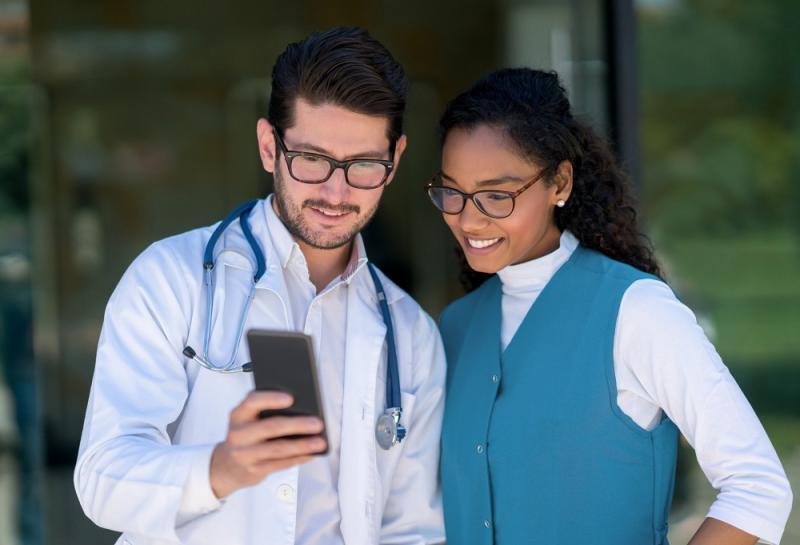 Two healthcare professionals looking at a phone
